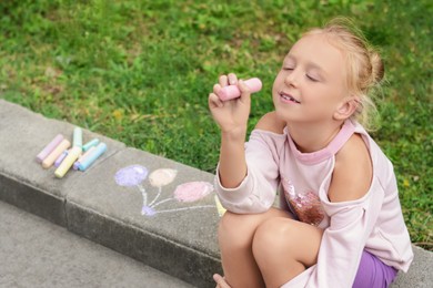 Photo of Little child chalk piece sitting on curb outdoors, space for text