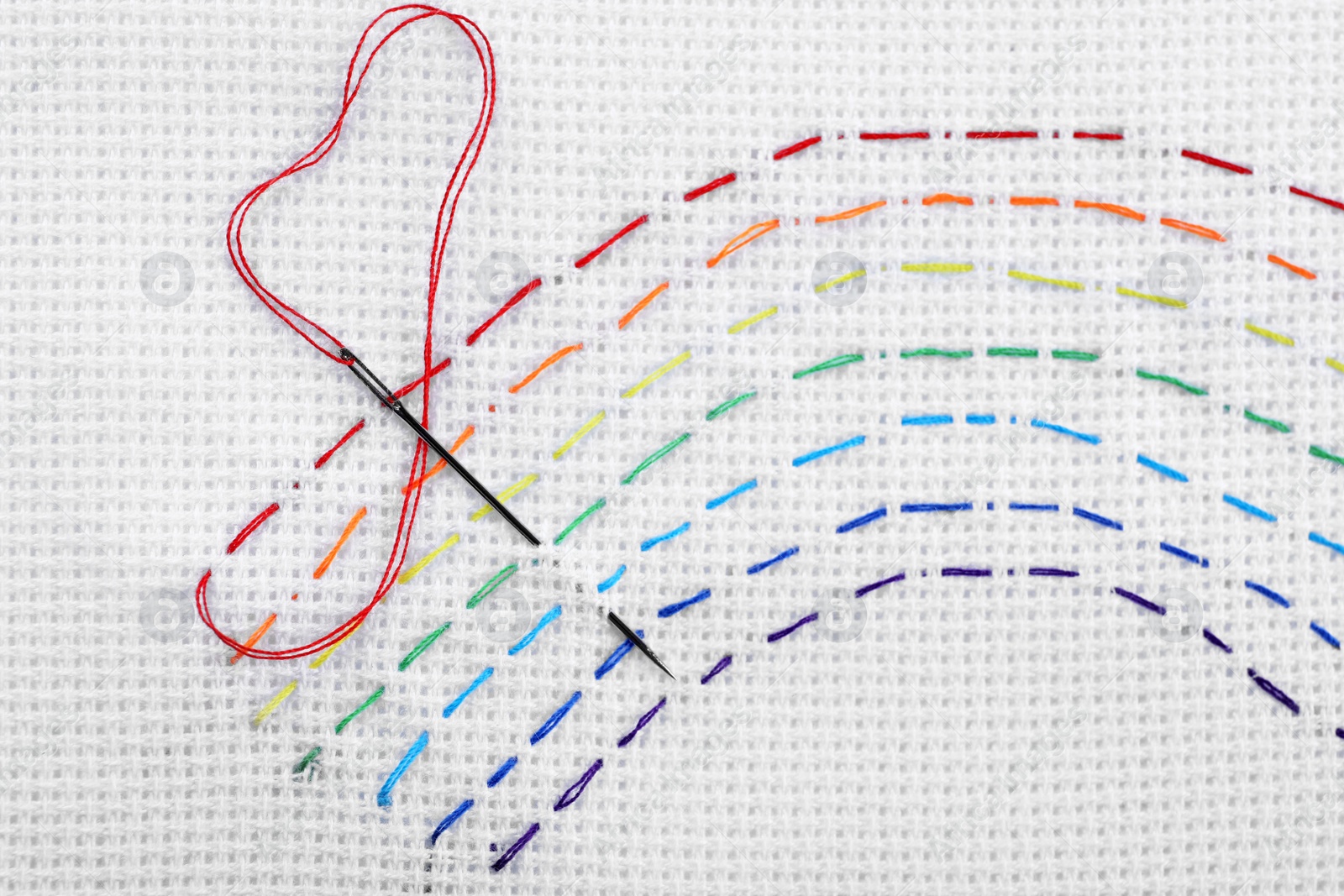 Photo of Canvas with embroidered rainbow and needle, top view