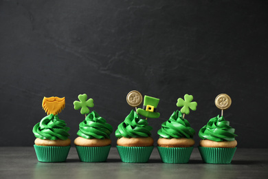 Photo of Delicious decorated cupcakes on grey table. St. Patrick's Day celebration