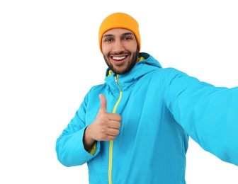 Smiling young man taking selfie and showing thumbs up on white background