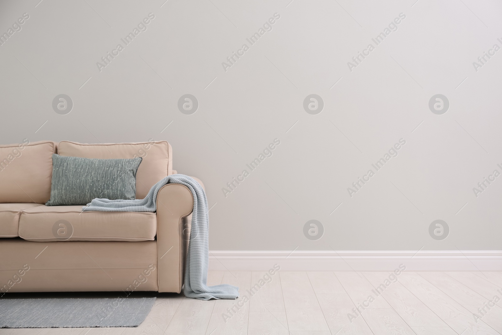 Photo of Comfortable beige sofa near light wall indoors, space for text. Simple interior