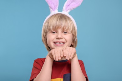 Photo of Happy boy wearing bunny ears headband on turquoise background. Easter celebration