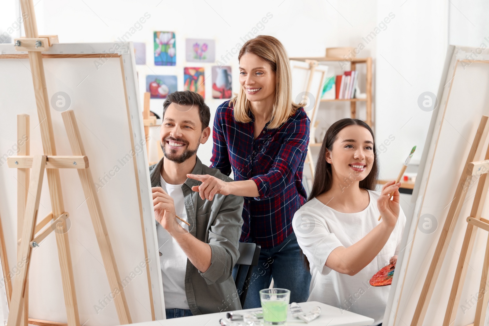 Photo of Artist teaching her students to paint in studio. Creative hobby