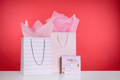 Shopping paper bags and gift box on red background