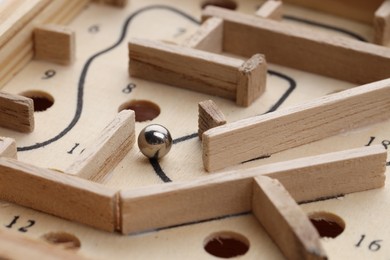 Photo of Wooden toy maze with metal ball, closeup