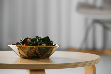 Decorative bowl with aromatic potpourri on wooden table in room, space for text