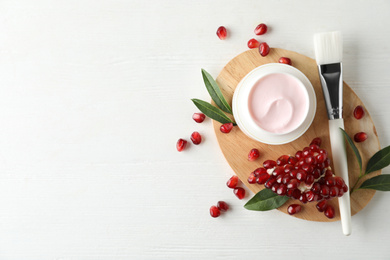 Flat lay composition with natural pomegranate facial mask on white wooden table. Space for text