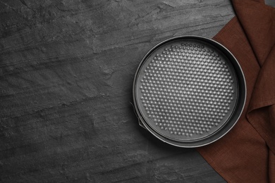 Baking dish and brown cloth on black table, flat lay with space for text. Cooking utensil