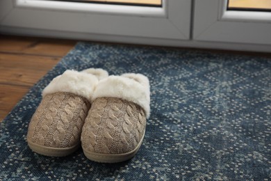 Photo of Pair of beautiful soft slippers on mat in room. Space for text