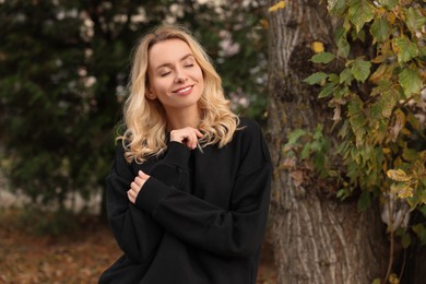 Photo of Happy woman in stylish warm sweater near tree outdoors