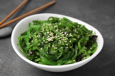 Photo of Tasty seaweed salad in bowl served on brown table, closeup