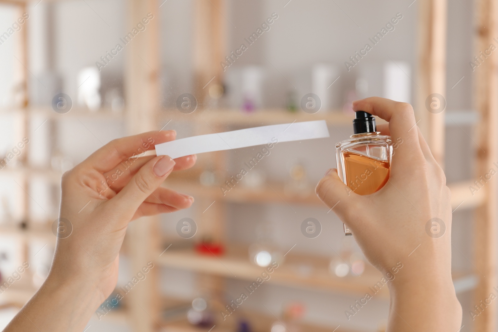 Photo of Woman with bottle of perfume and blotter indoors, closeup