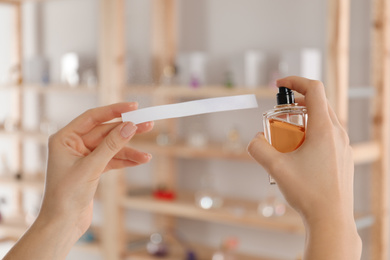 Woman with bottle of perfume and blotter indoors, closeup