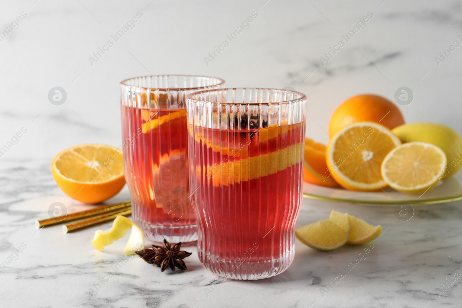 Photo of Aromatic punch drink and ingredients on white marble table