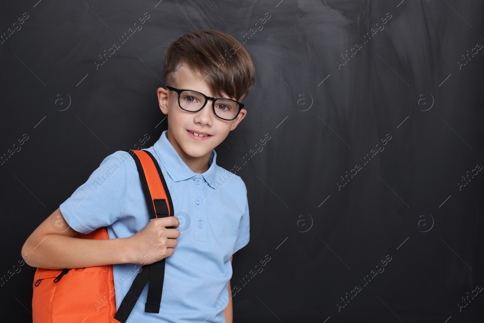 Photo of Cute schoolboy in glasses near chalkboard, space for text