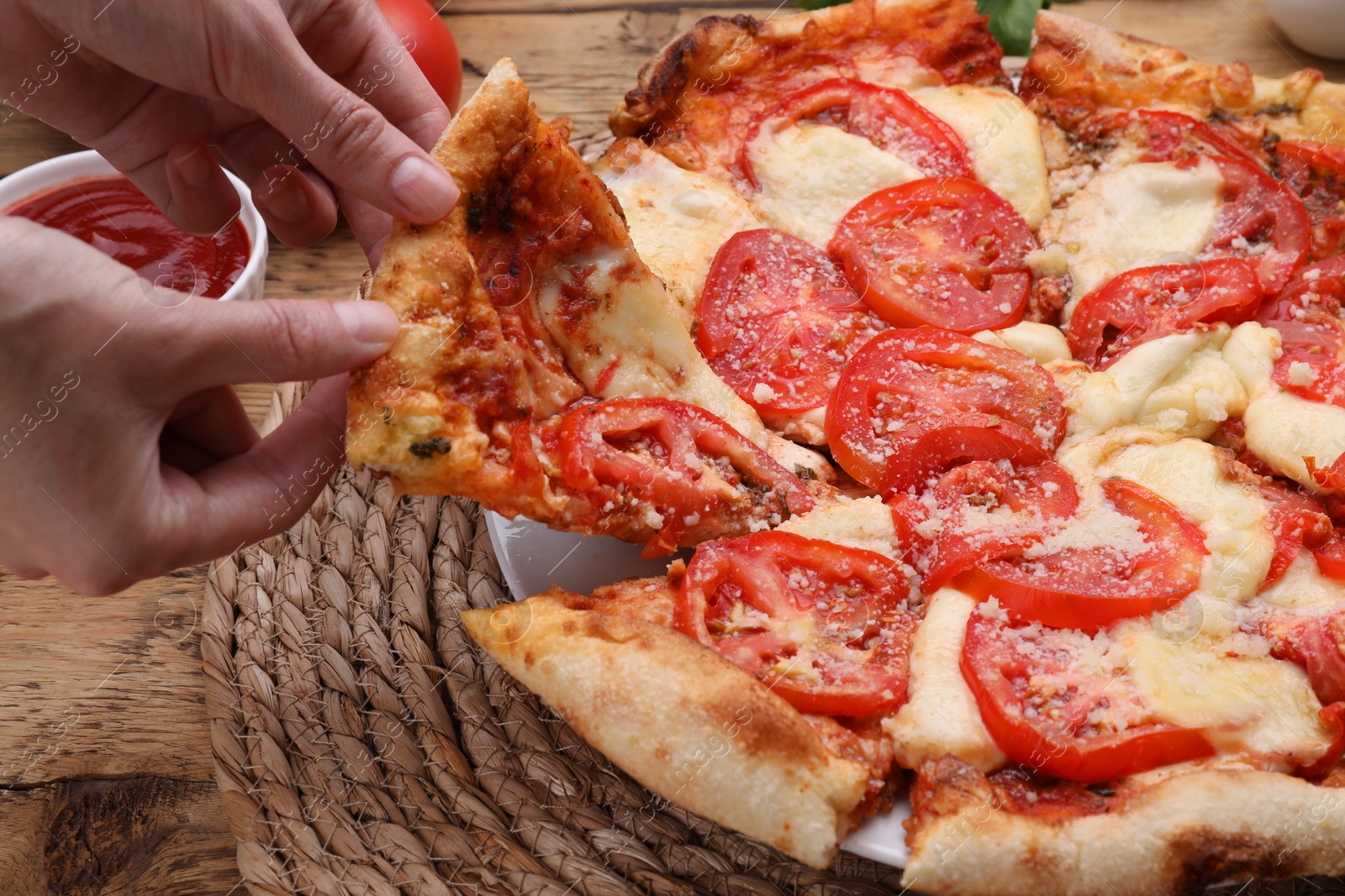 Photo of Woman taking piece of delicious Caprese pizza at wooden table, closeup