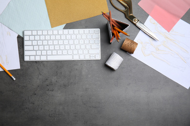 Flat lay composition with keyboard and accessories on grey stone table, space for text. Designer's workplace