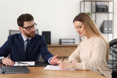 Woman signing document while having meeting with lawyer in office