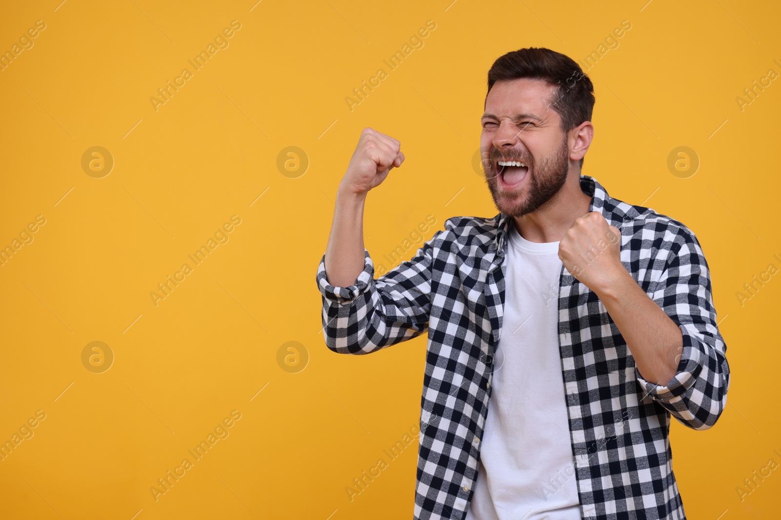 Photo of Emotional sports fan celebrating on yellow background. Space for text