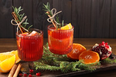 Photo of Christmas Sangria cocktail in glasses, ingredients and fir tree branches on wooden table