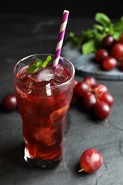 Photo of Delicious grape soda water on black table. Refreshing drink