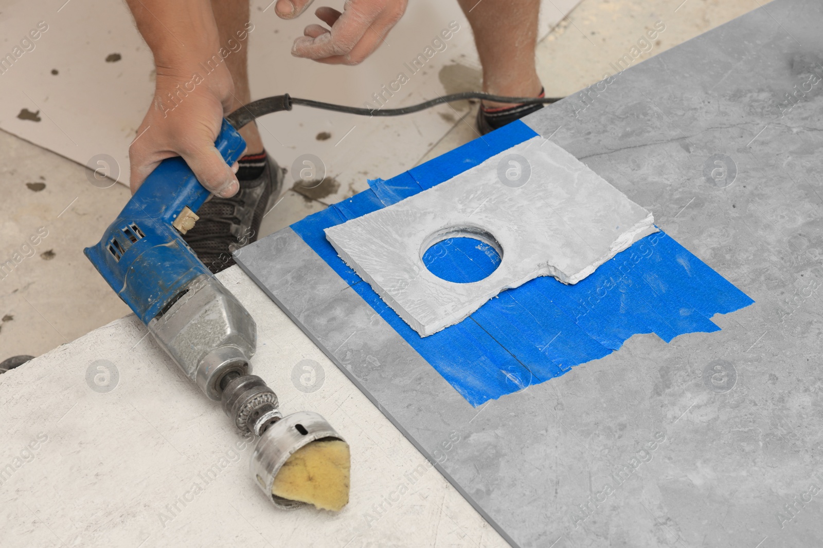 Photo of Worker making socket hole in tile indoors, closeup