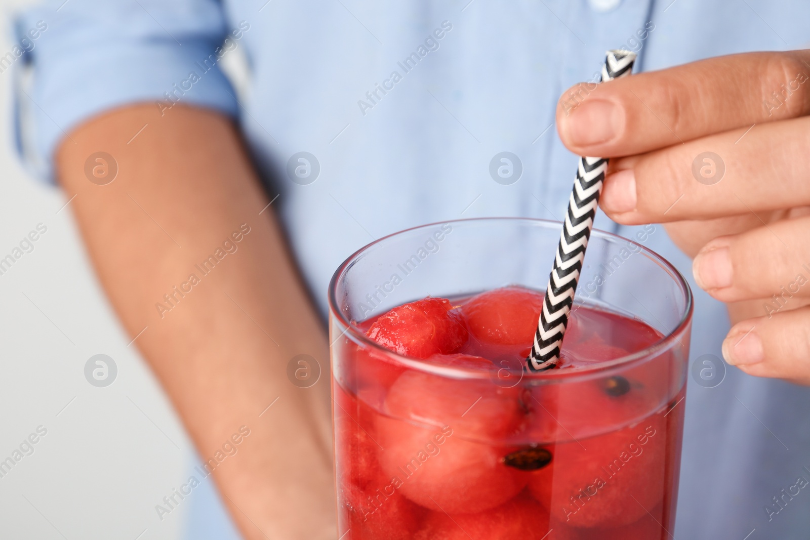 Photo of Woman holding glass of watermelon ball cocktail with straw, closeup