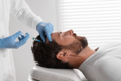 Photo of Trichologist giving injection to patient in clinic, closeup