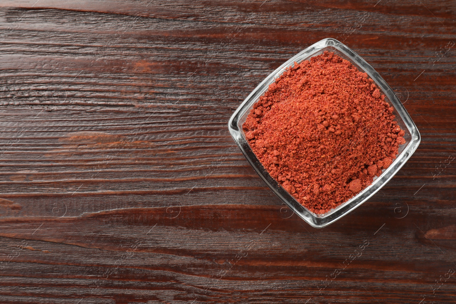 Photo of Dried cranberry powder in glass bowl on wooden table, top view. Space for text