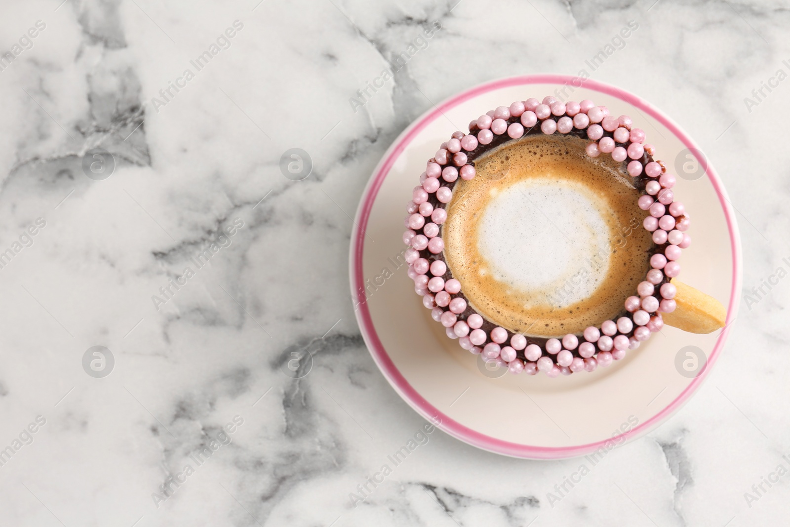 Photo of Delicious edible biscuit cup of coffee decorated with sprinkles on white marble table, top view. Space for text