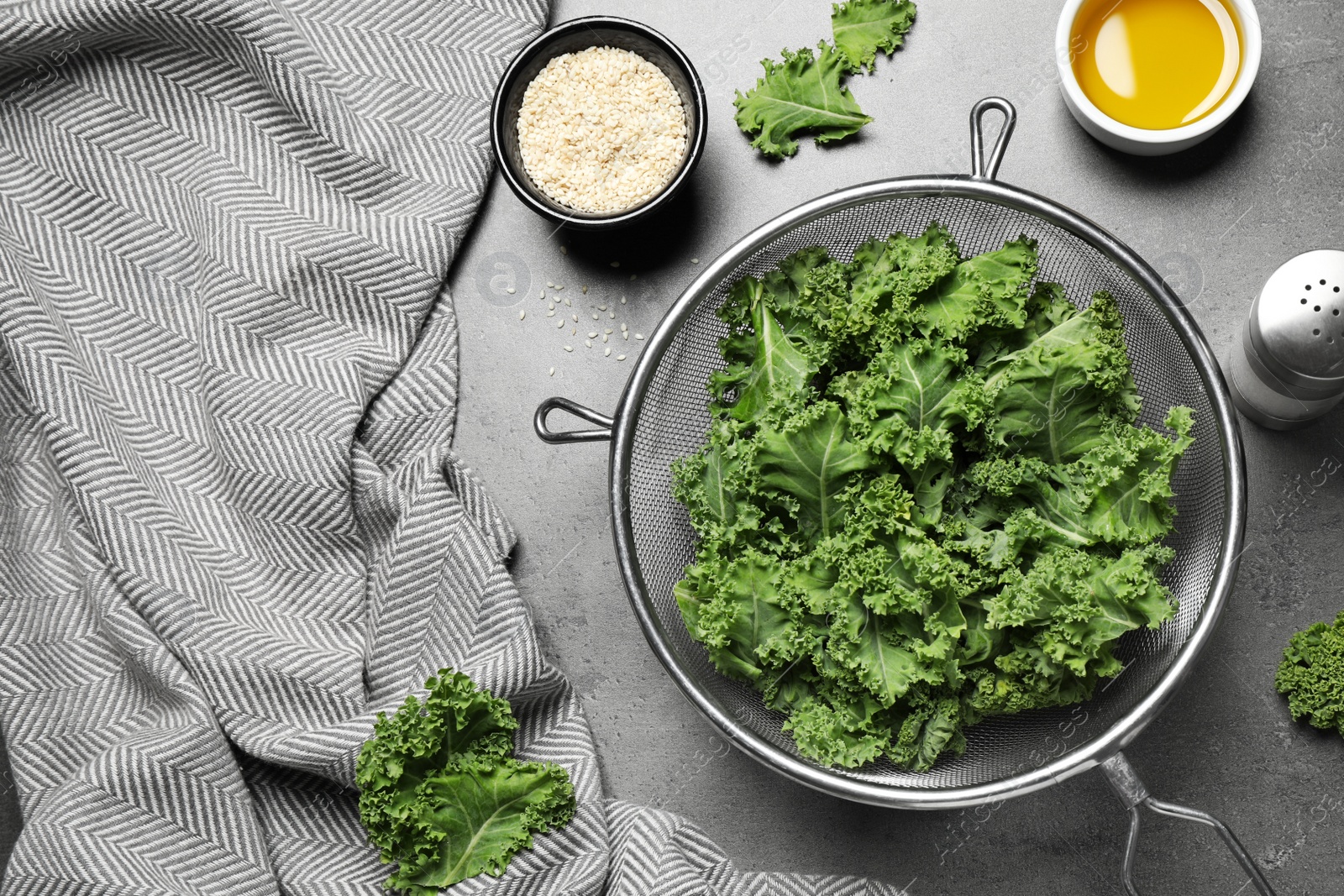 Photo of Raw cabbage leaves on grey table, flat lay. Preparing kale chips