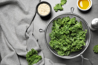 Photo of Raw cabbage leaves on grey table, flat lay. Preparing kale chips