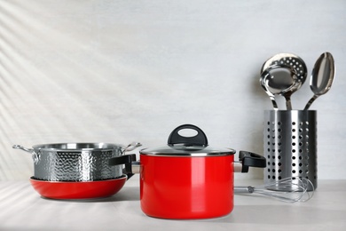 Photo of Set of clean cookware on table against light background