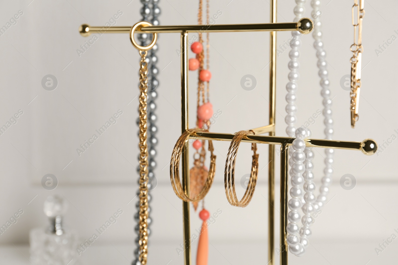 Photo of Holder with set of luxurious jewelry against light background, closeup