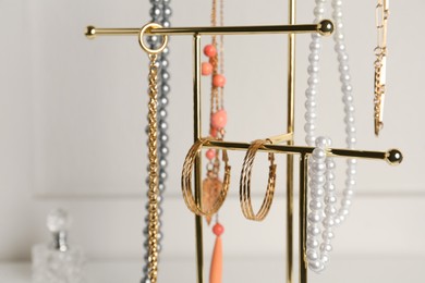 Holder with set of luxurious jewelry against light background, closeup