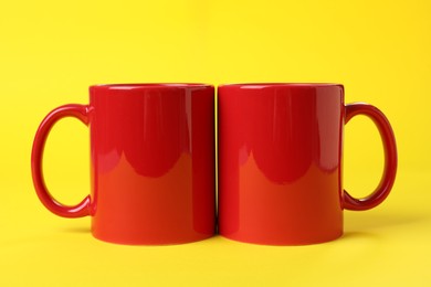 Photo of Two red ceramic mugs on yellow background