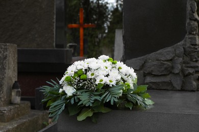 Funeral wreath of flowers on granite tombstone in cemetery