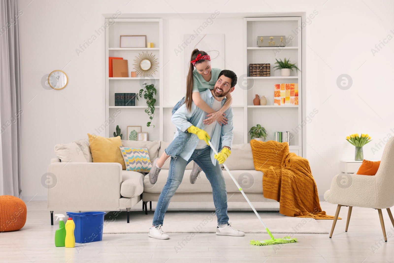 Photo of Spring cleaning. Couple having fun while tidying up living room