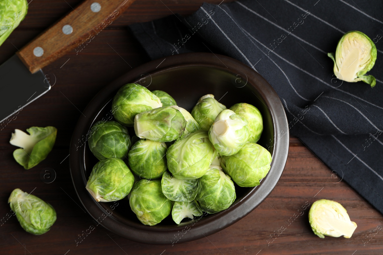 Photo of Fresh Brussels sprouts on brown wooden table, flat lay