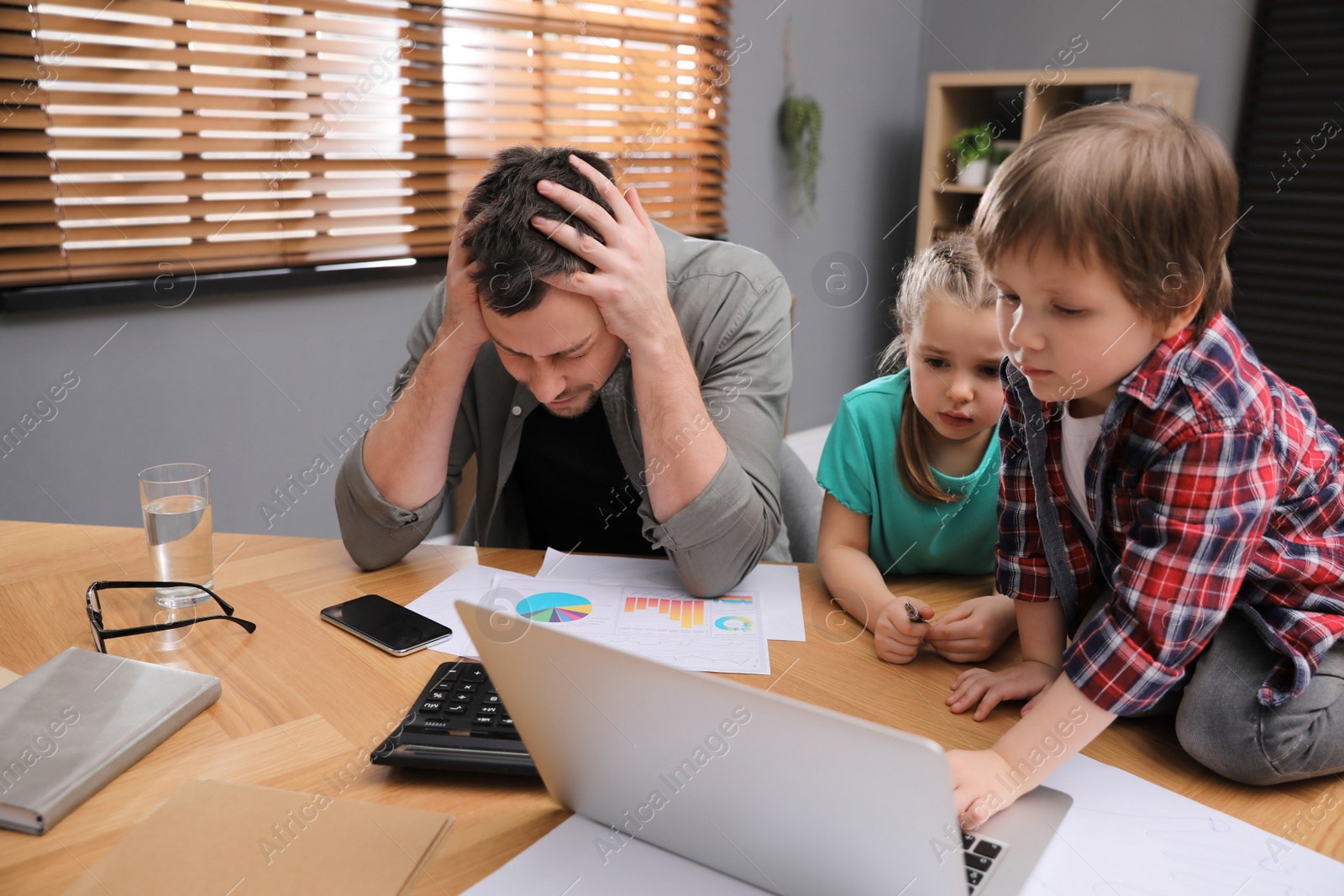 Photo of Overwhelmed man combining parenting and work at home