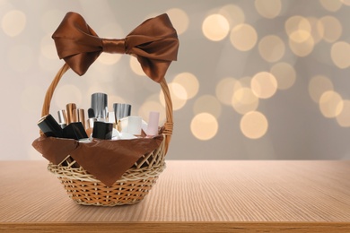 Image of Wicker basket full of cosmetic products on table against blurred festive lights. Space for text