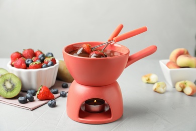 Photo of Fondue pot with chocolate and different products on grey table