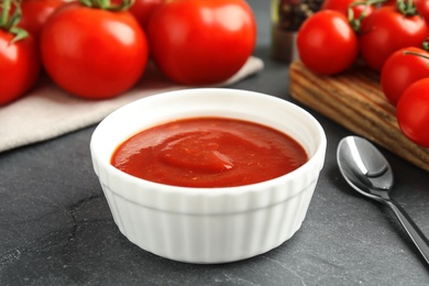 Photo of Composition with bowl of tomato sauce on grey table