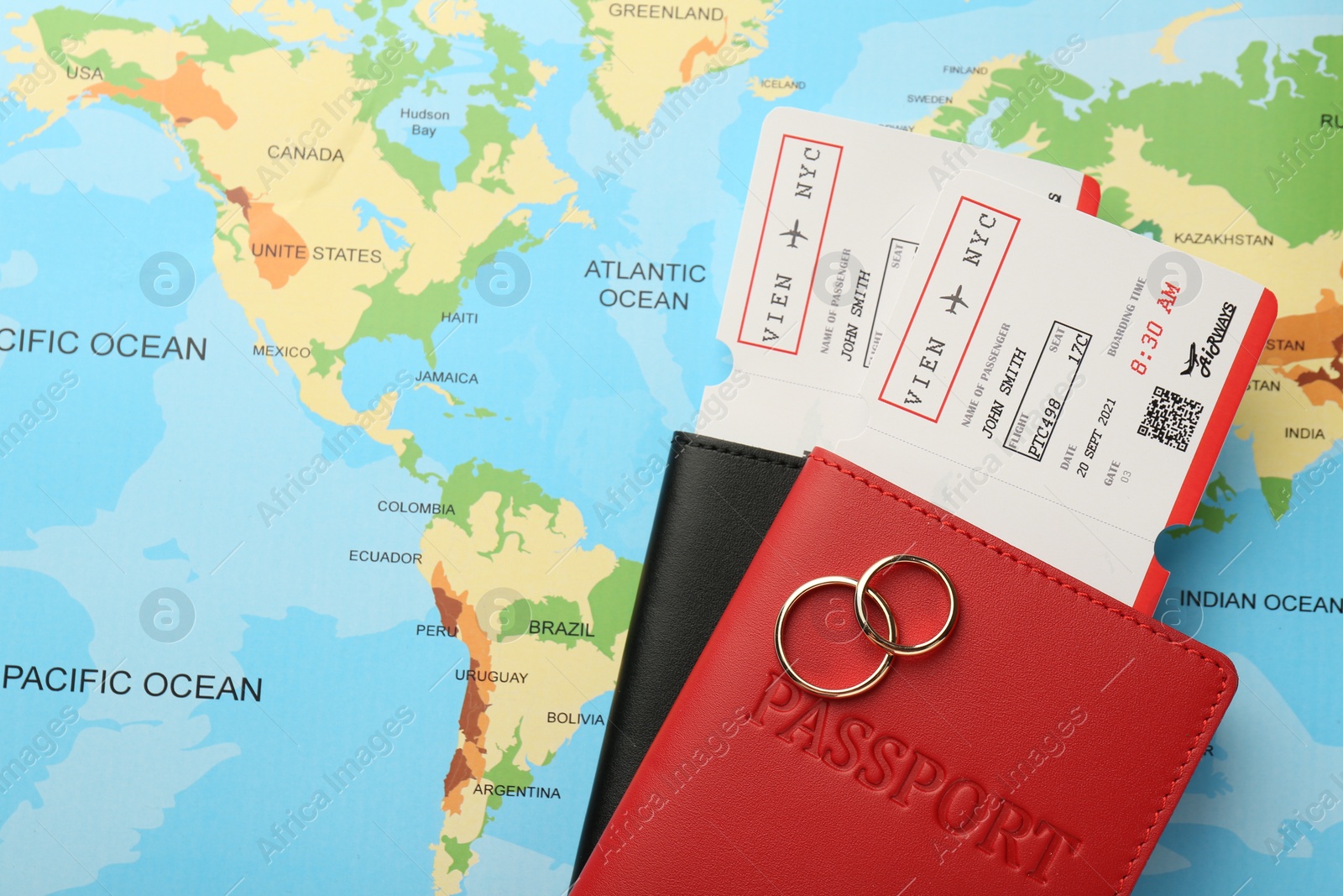 Photo of Honeymoon concept. Plane tickets, passports and golden rings on world map, top view