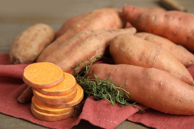 Photo of Napkin with thyme and sweet potatoes on table, closeup