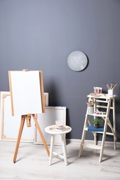 Photo of Artist's workshop interior with easel and set of professional equipment. Space for design