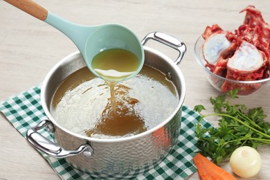 Photo of Delicious homemade bone broth and ingredients on wooden table