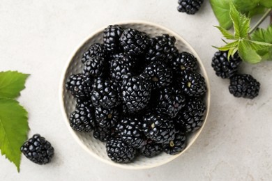 Tasty ripe blackberries and leaves on white table, flat lay