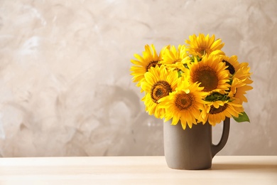 Photo of Jug with beautiful yellow sunflowers on table