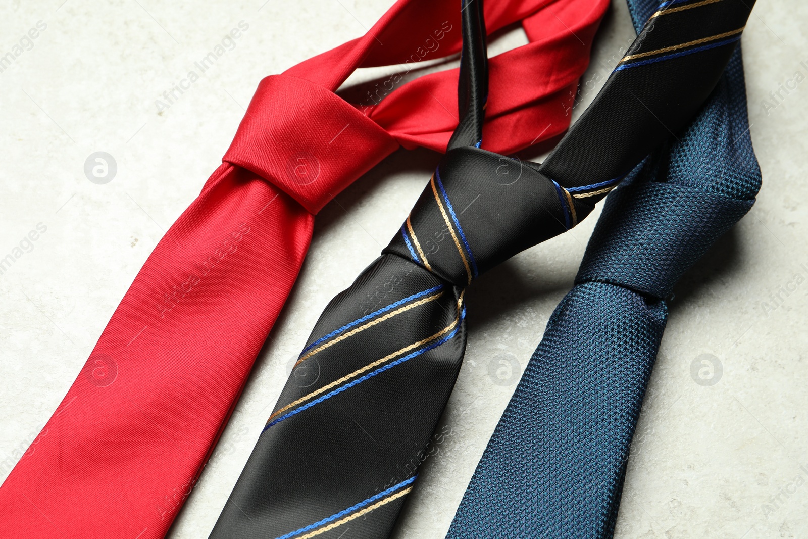 Photo of Different neckties on light textured table, above view. Space for text